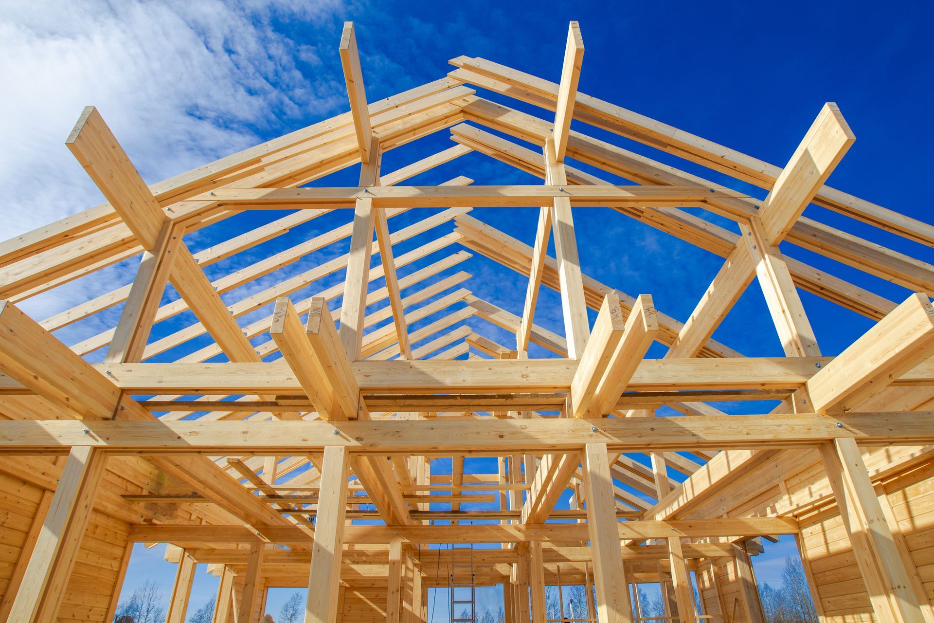 A wooden structure of a house under construction with a blue sky in the background.