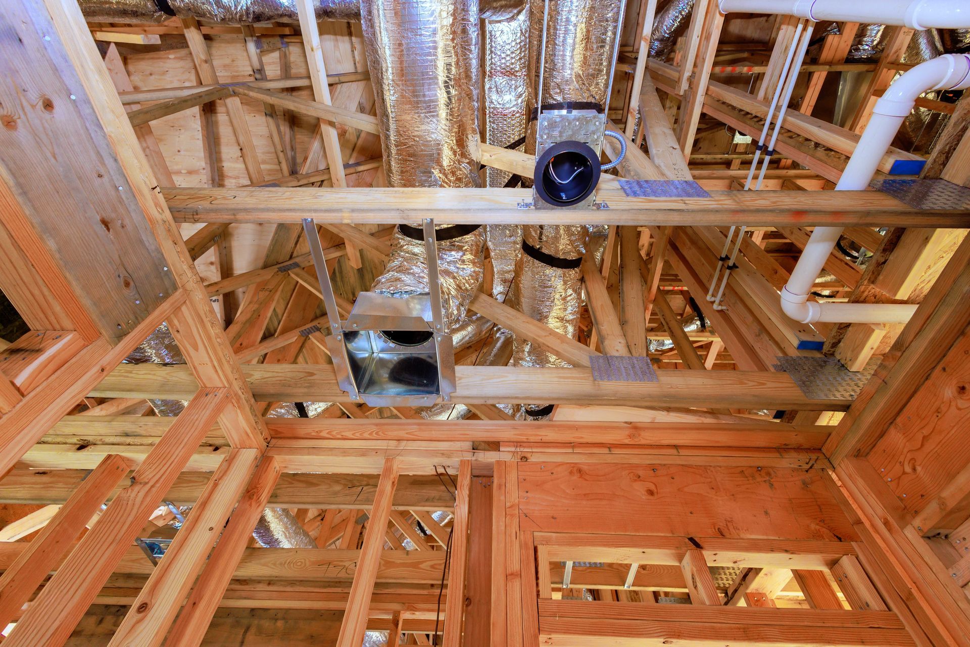 The ceiling of a house under construction with pipes and ducts.