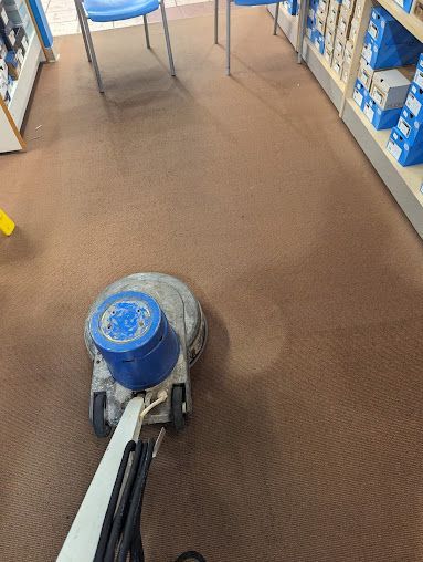 A person is using a machine to clean a carpet in a store.