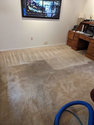 A living room with a carpet , desk , and television.