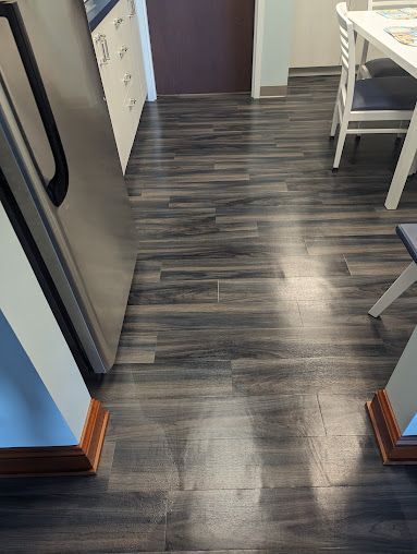 A kitchen with a wooden floor and a stainless steel refrigerator.