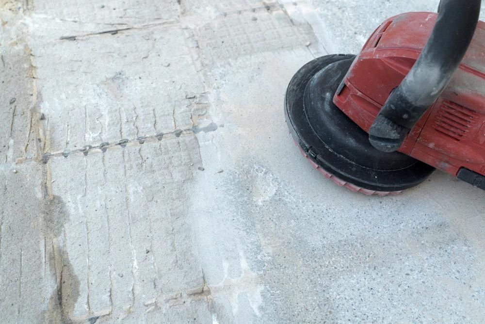 A Person Is Using a Grinder on A Concrete Surface — TNT Floor Removal & Demolition in Tewantin, QLD