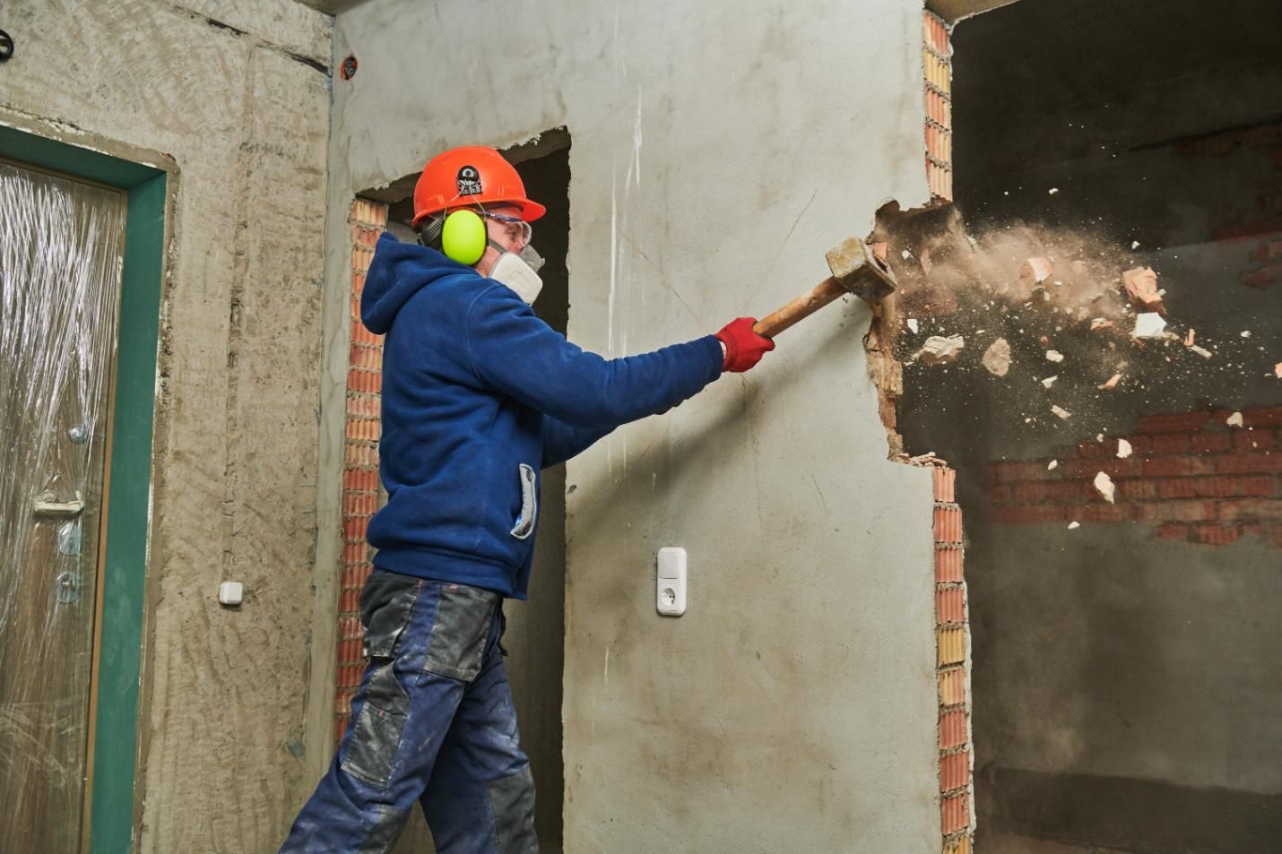 A Man Is Breaking a Wall with A Hammer — TNT Floor Removal & Demolition in Tewantin, QLD