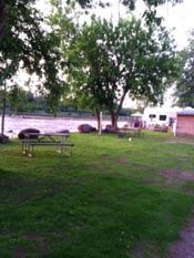 A picnic table is sitting in the grass next to a lake.