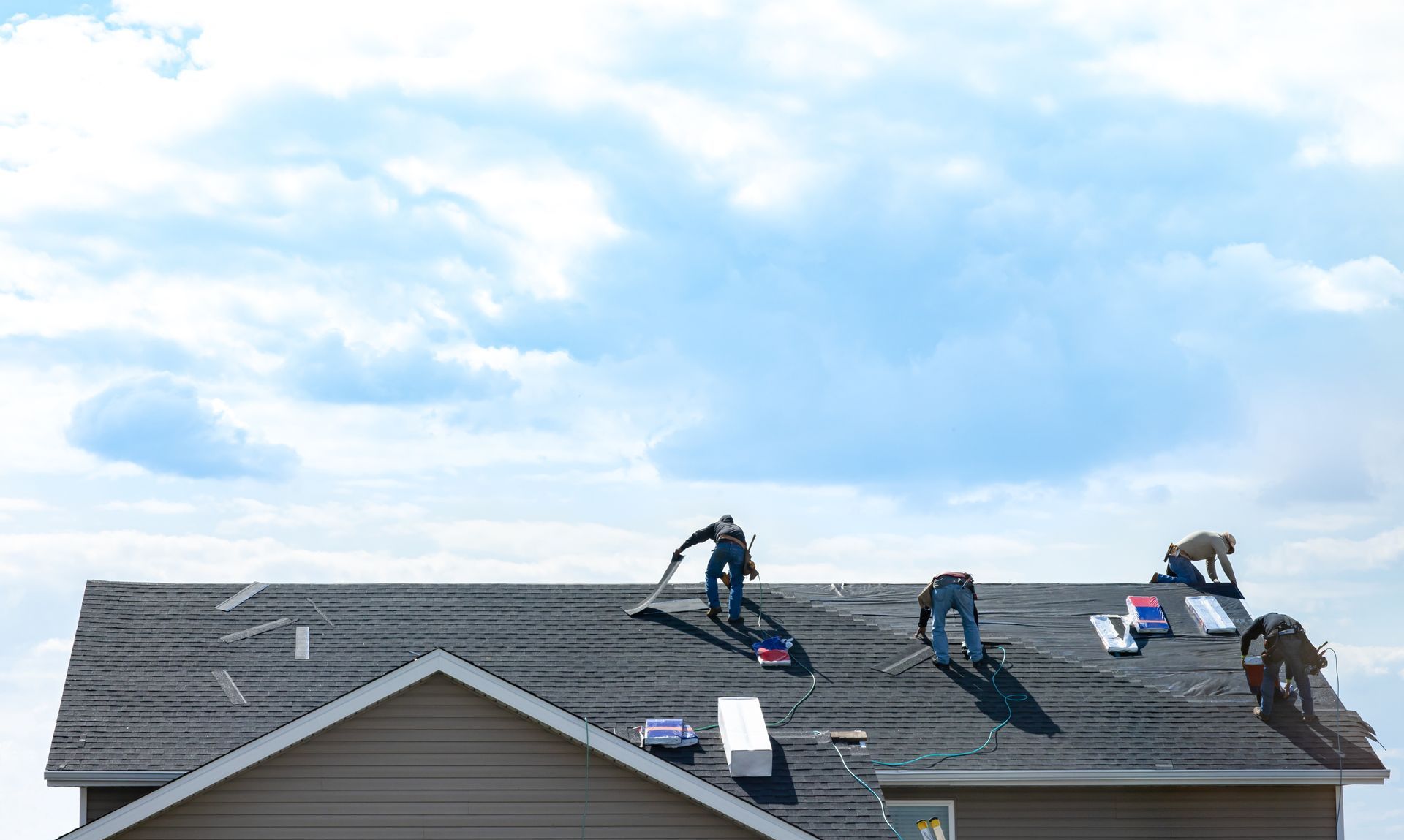 A man is working on a roof with a hammer.