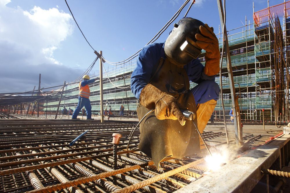 A man is welding a piece of metal on a construction site.