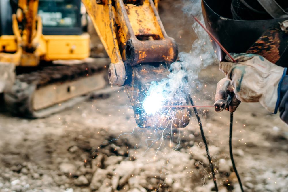 A man is welding a piece of metal on a construction site.