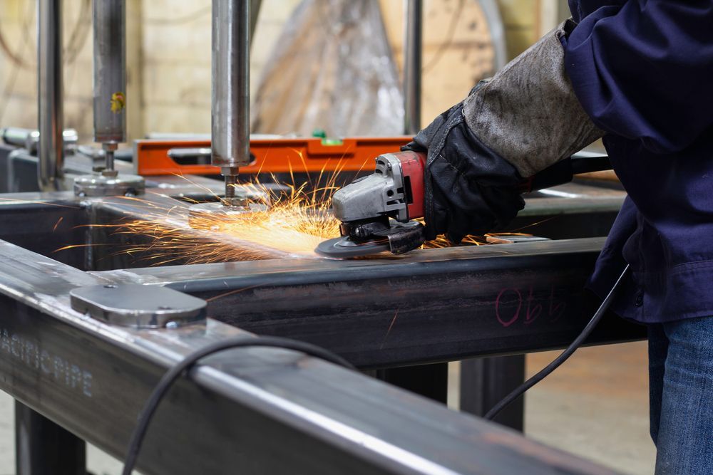 A person is grinding a piece of metal in a factory.