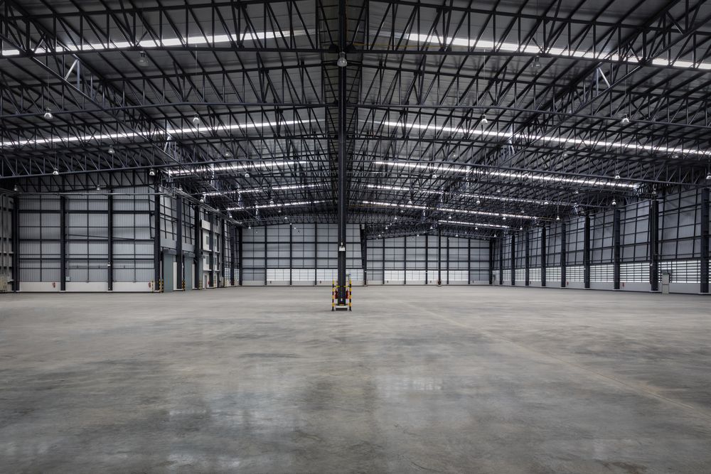 An empty warehouse with a concrete floor and a metal roof.