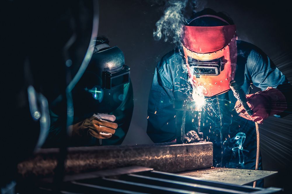 A man wearing a welding mask is welding a piece of metal.