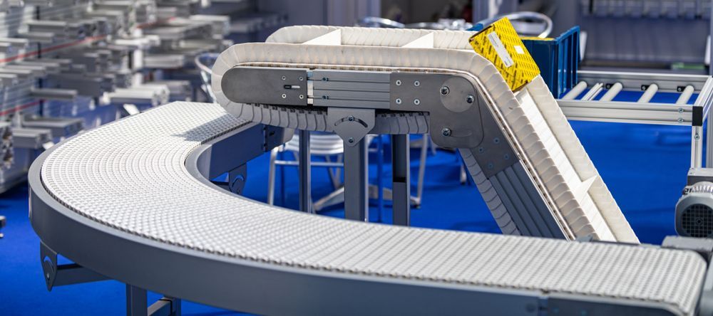 A conveyor belt is going down a blue floor in a factory.
