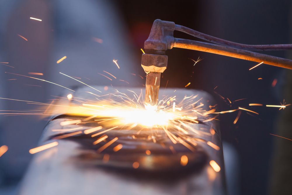 A close up of a person welding a piece of metal with sparks coming out of it.