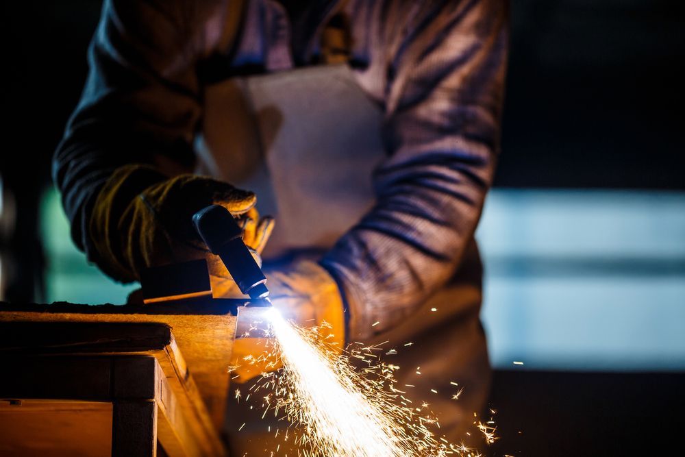 A man is welding a piece of metal in a dark room.