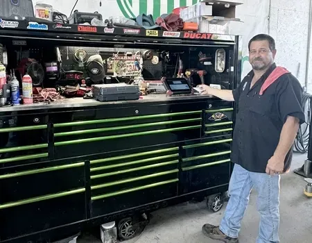Car's side panel covered with plastic sheeting in a body shop, ready for painting.
