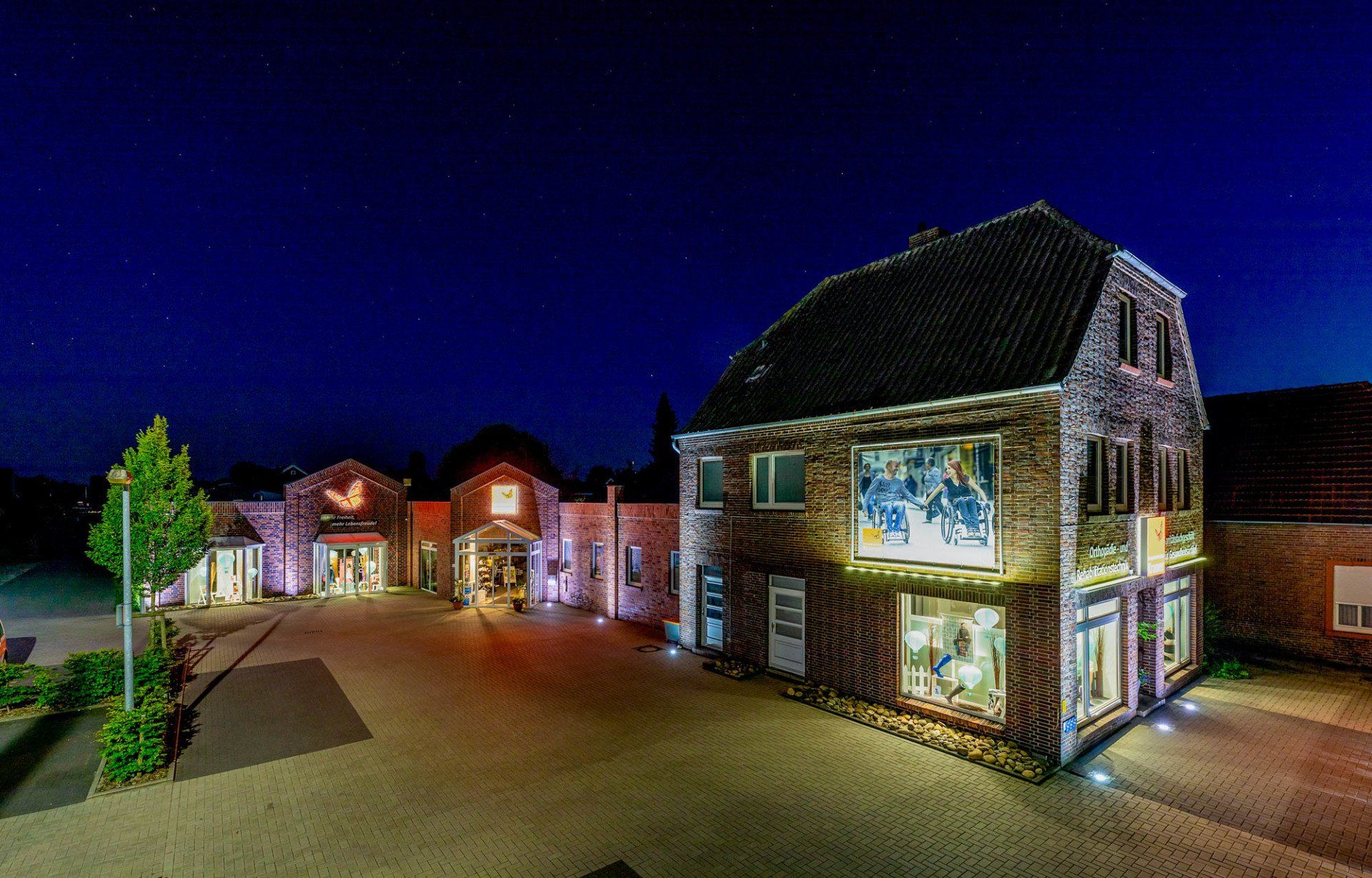 Ein großes Backsteingebäude mit vielen Fenstern ist nachts beleuchtet.