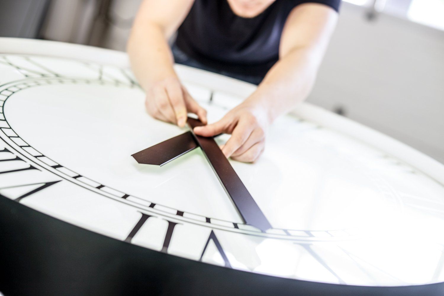 Eine Person stellt die Zeiger einer großen Uhr ein