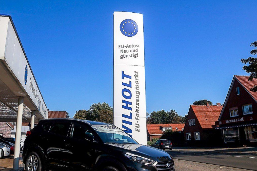 Vor einem Autohaus parkt ein schwarzes Auto.