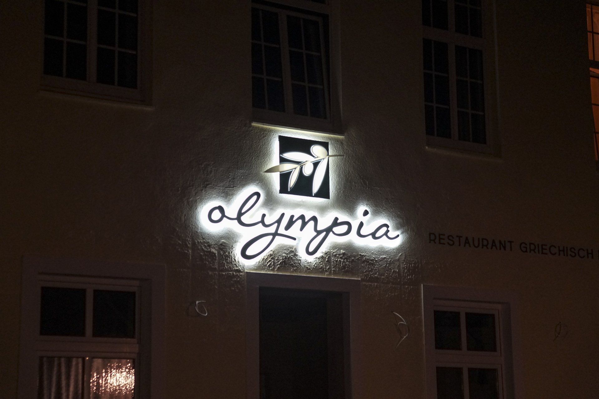 Das Restaurant Olympia ist nachts beleuchtet.