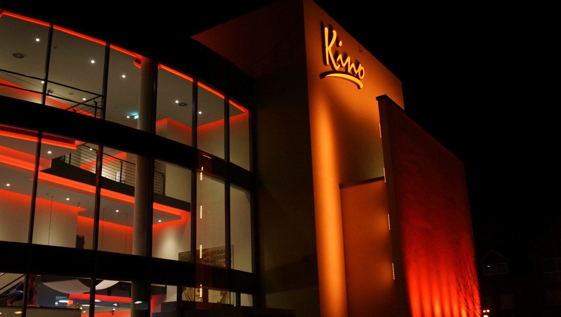 Ein großes Gebäude mit vielen Fenstern ist nachts beleuchtet.