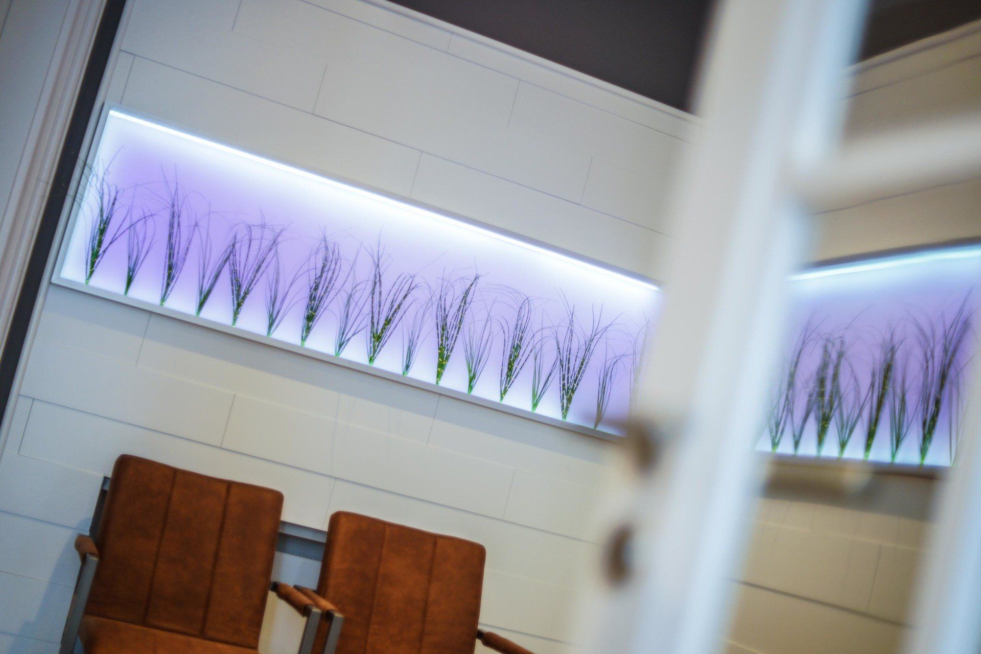 Ein Wartezimmer mit zwei Stühlen und einem Gemälde an der Wand.