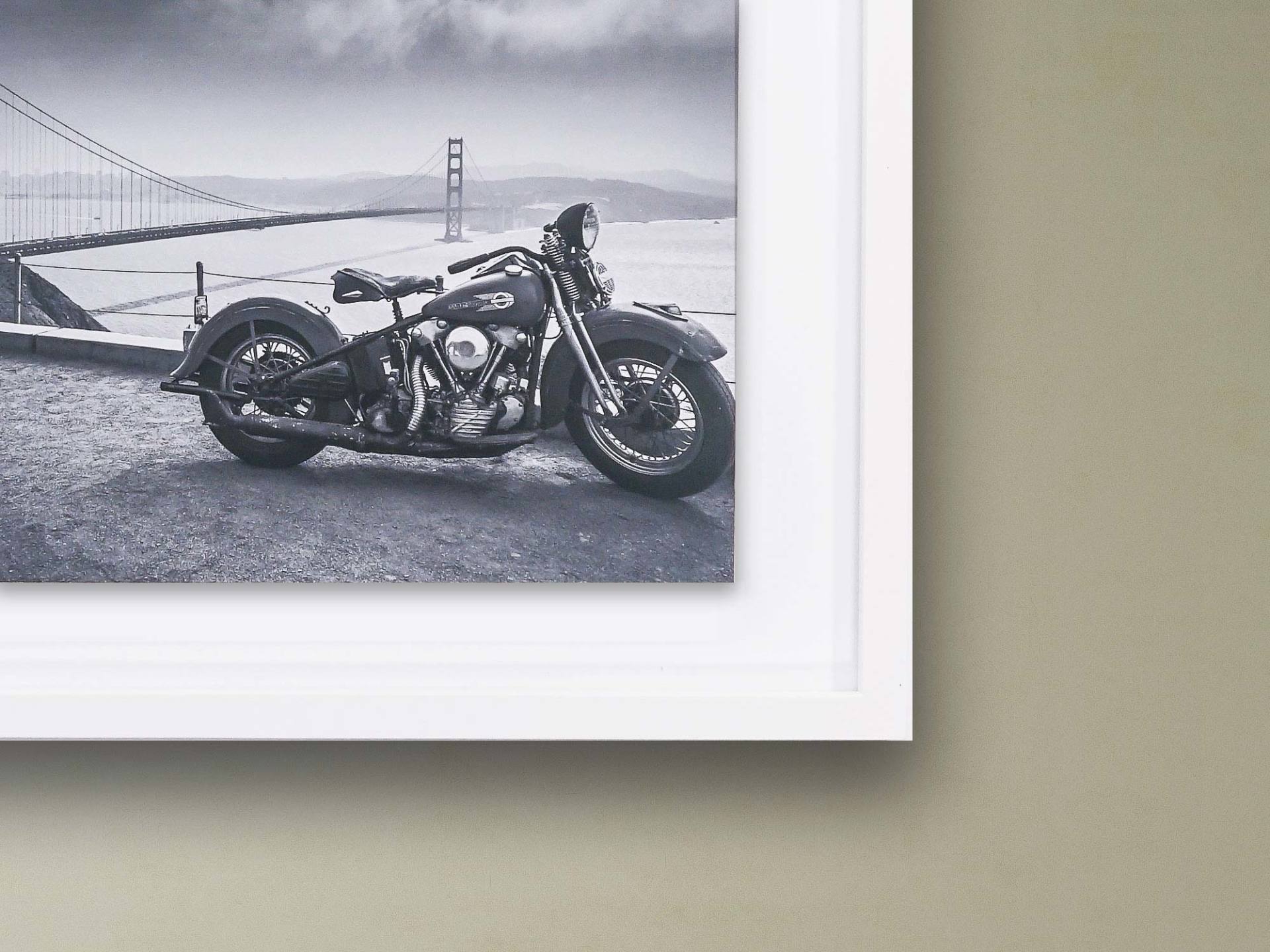 Ein Schwarzweißfoto eines Motorrades mit einer Brücke im Hintergrund