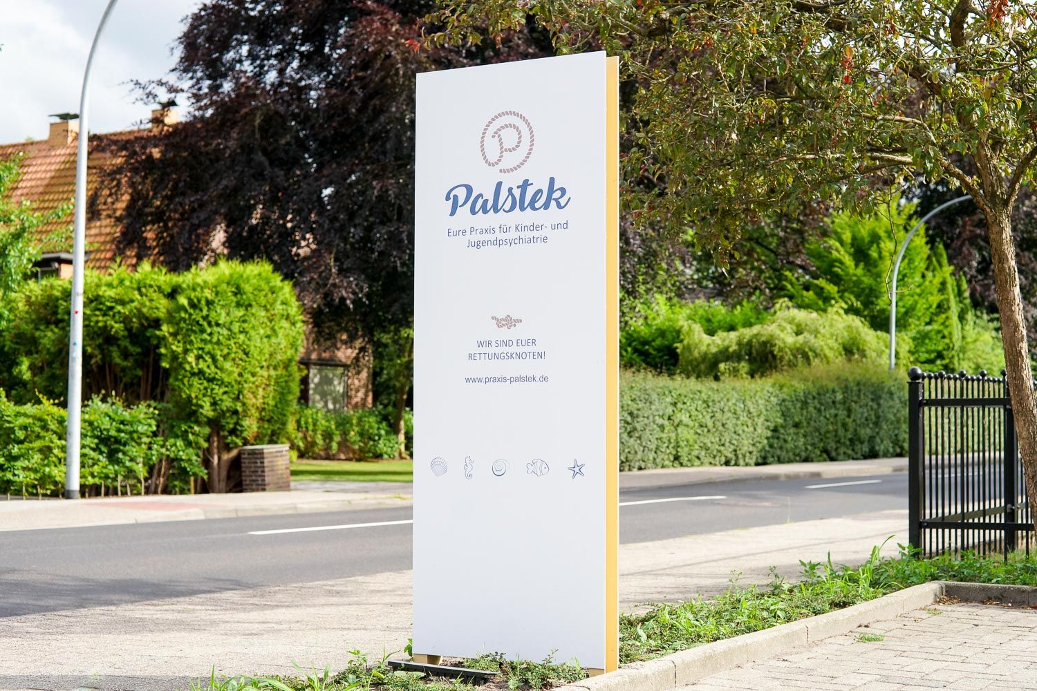 Am Straßenrand steht ein weiß-gelbes Schild.