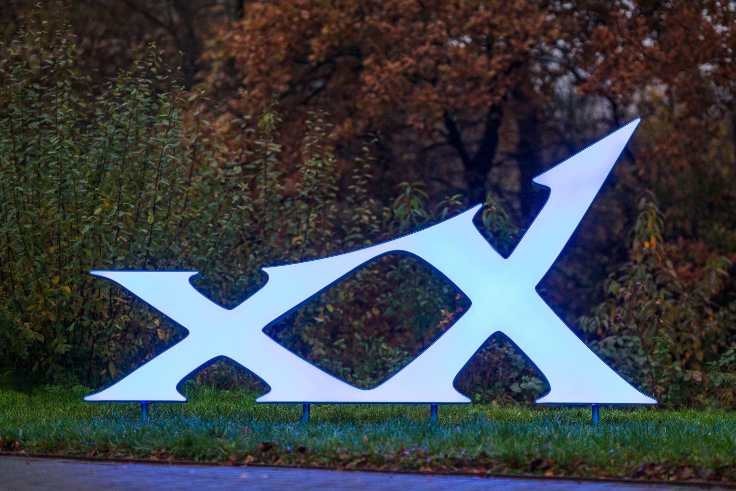 Ein großes weißes x auf einer Wiese mit Bäumen im Hintergrund