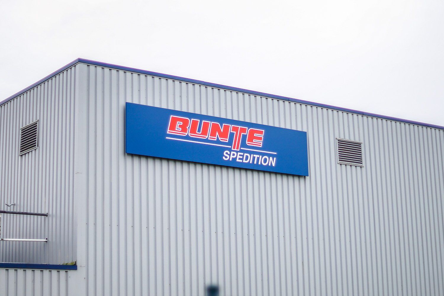 Ein großes Gebäude mit einem blauen Schild mit der Aufschrift „Dunte Spedition“.