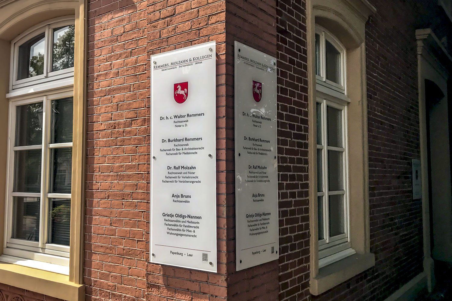 Zwei Schilder an der Seite eines Backsteingebäudes