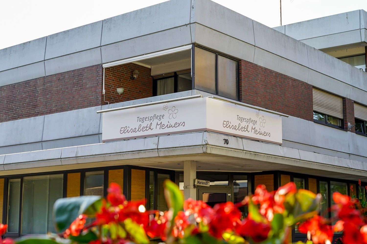 Ein Gebäude mit einem Balkon und Blumen davor.