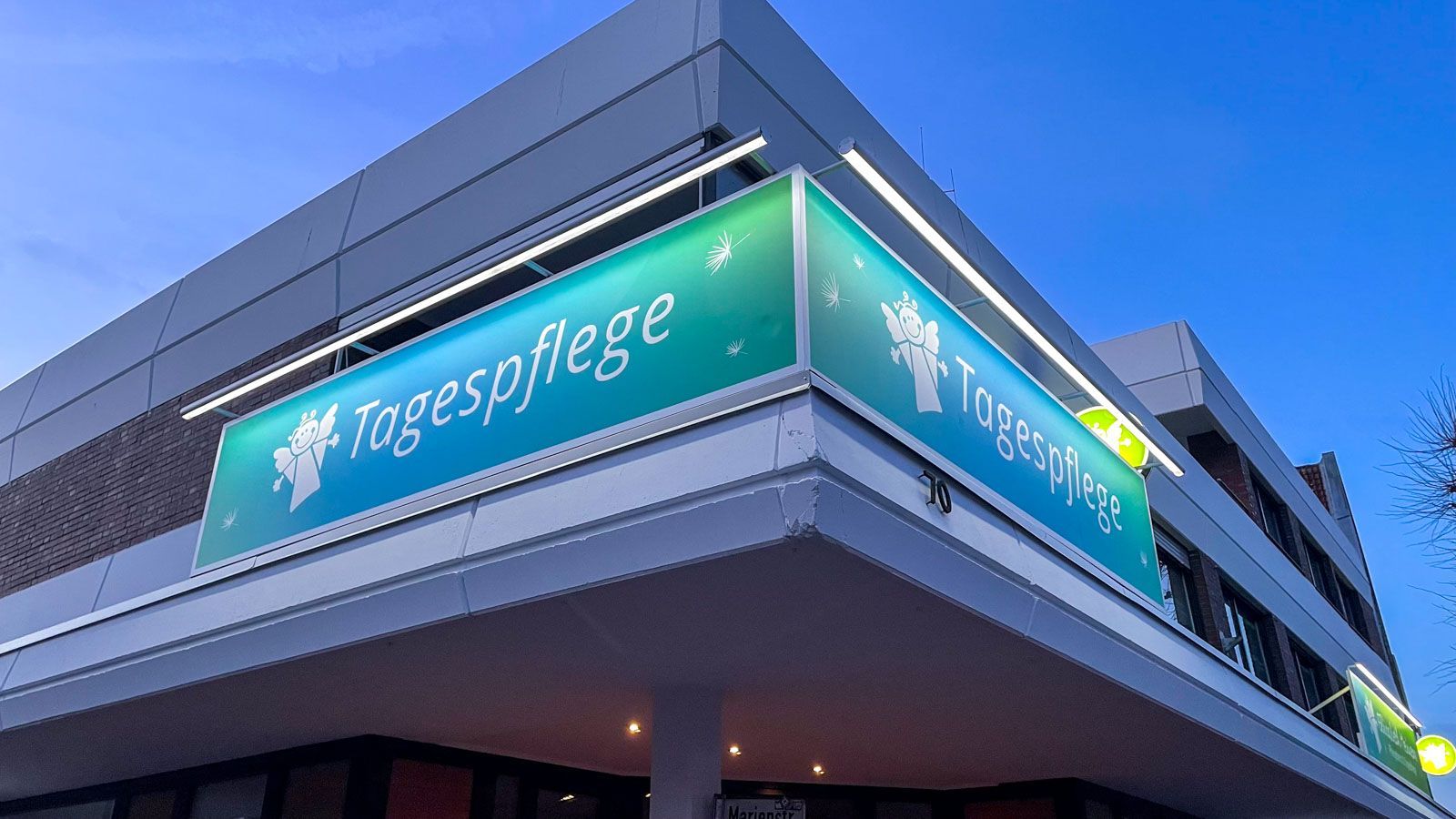 Ein grünes Schild an der Seite eines Gebäudes mit der Aufschrift „Tagespflege“