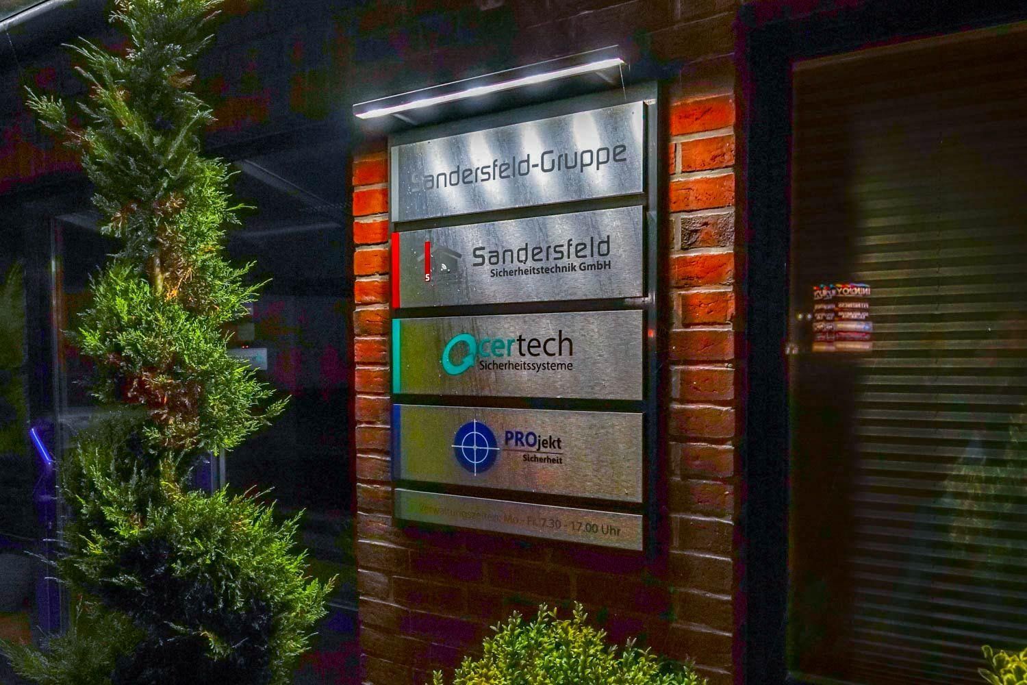 Eine Reihe von Schildern an einer Backsteinmauer neben einem Baum.