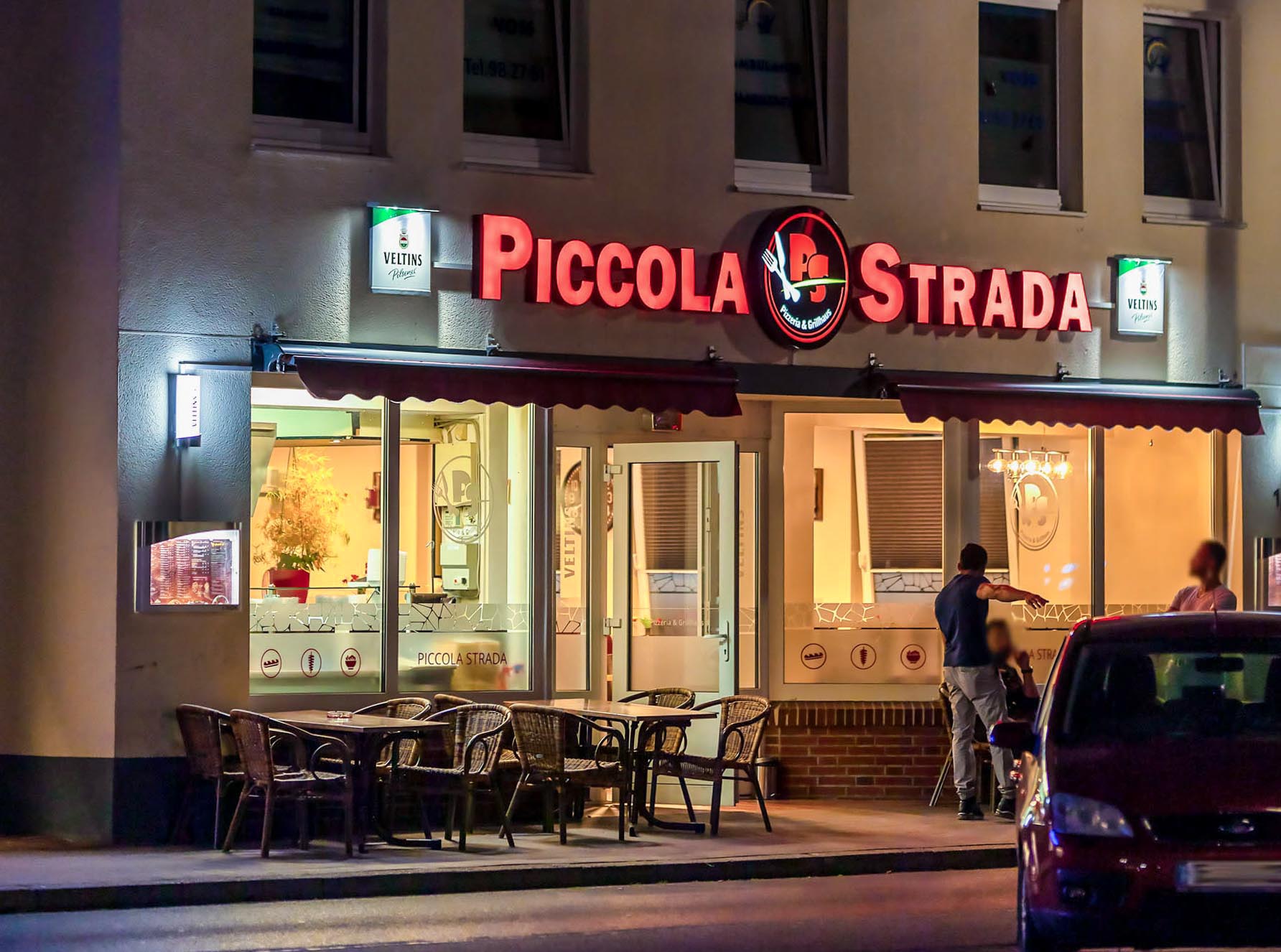 Ein Restaurant namens Piccola Strada ist nachts beleuchtet