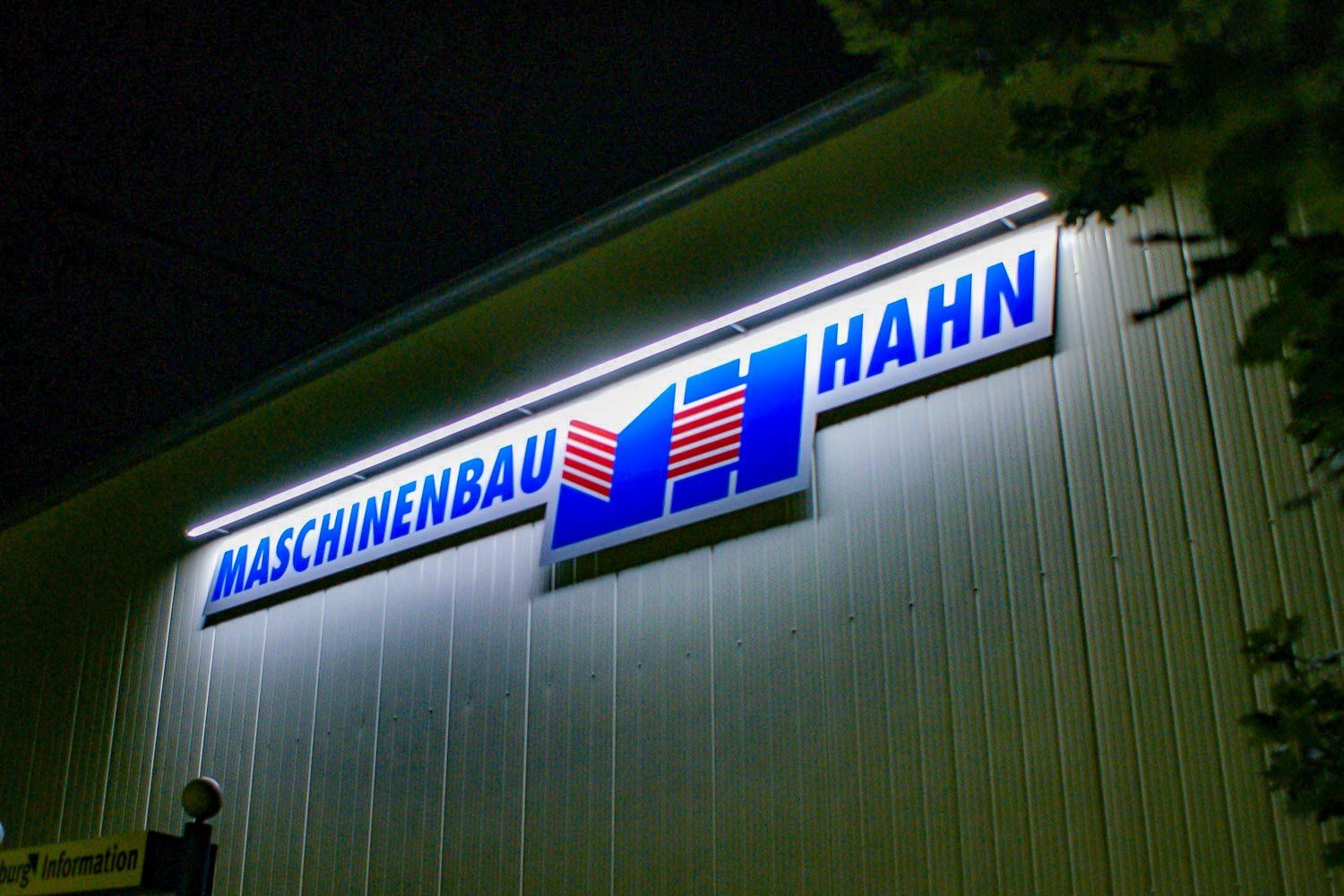 Maschinenbau Hahn ist nachts an der Seite eines Gebäudes beleuchtet