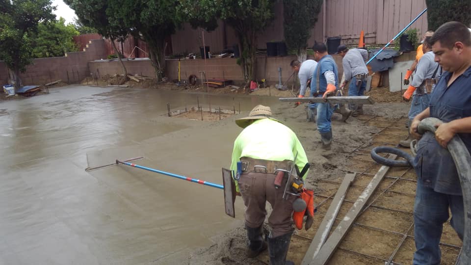 A group of construction workers are working on a concrete driveway.