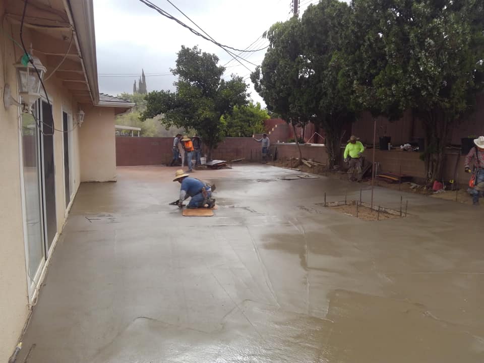 A group of people are working on a concrete driveway