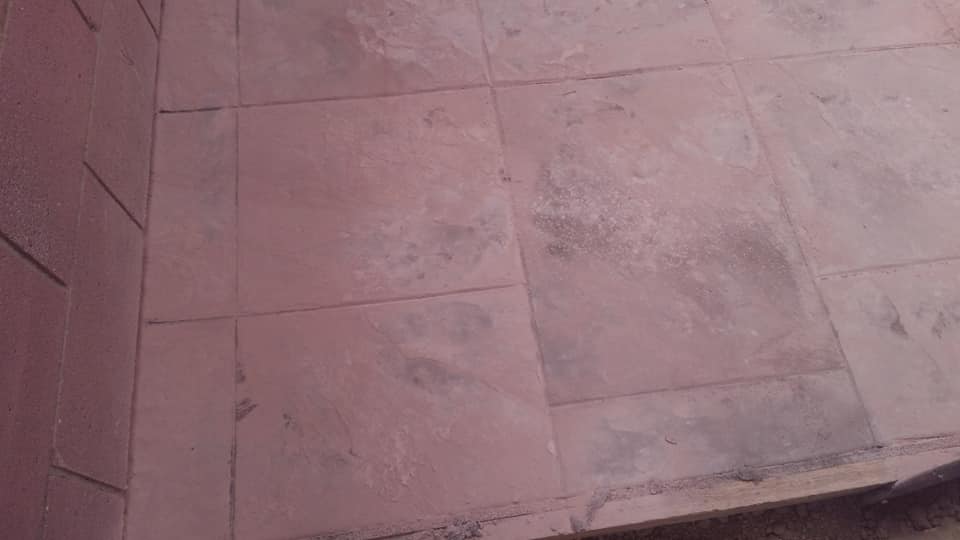 A close up of a tiled floor with a brick wall in the background.