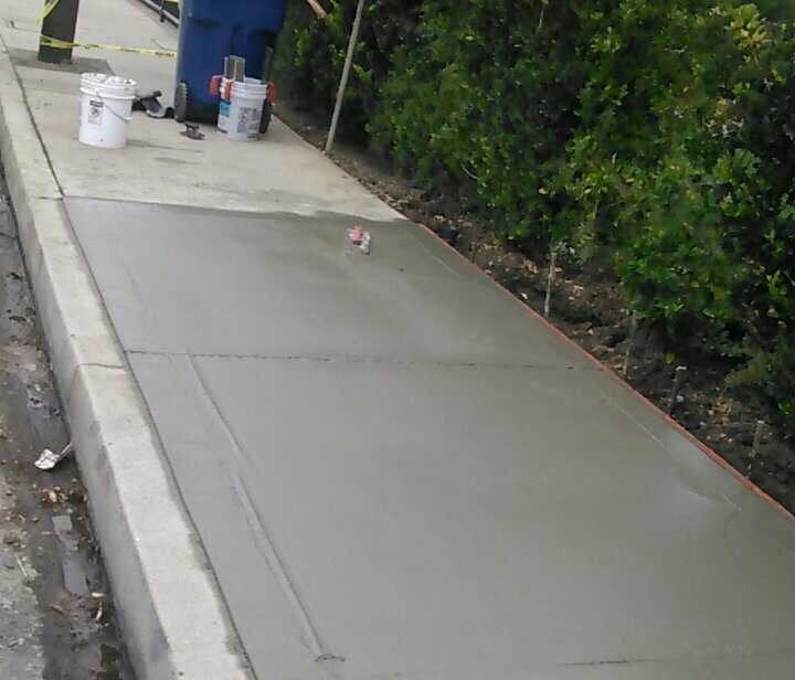 A person is painting a sidewalk with buckets of paint.