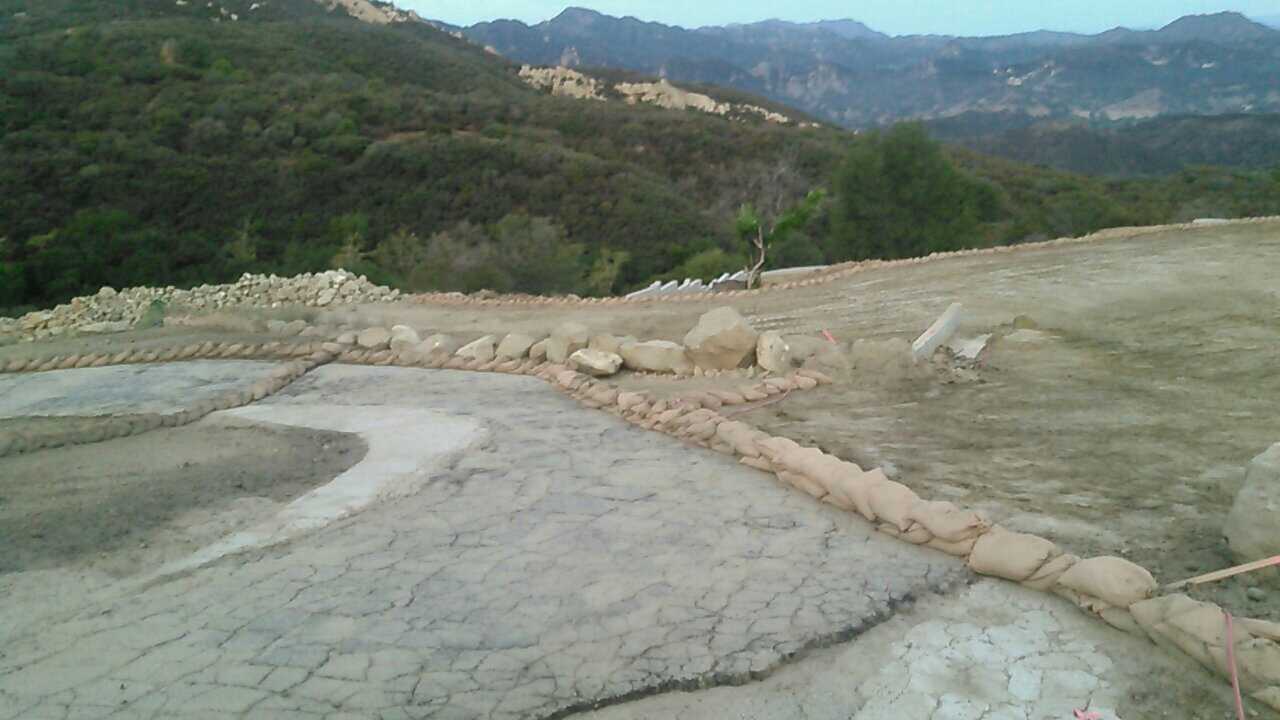 A dirt road going through a valley with mountains in the background.