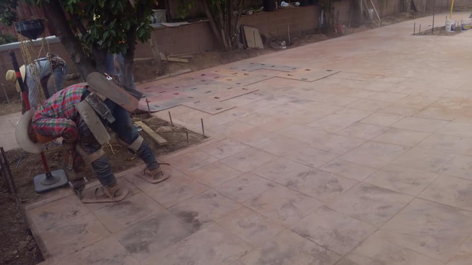 A group of construction workers are working on a concrete driveway.