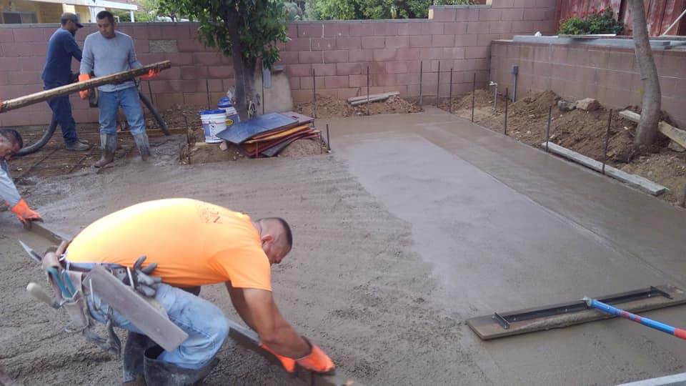 A group of construction workers are working on a concrete driveway.