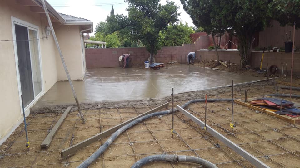 A concrete driveway is being built in the backyard of a house.