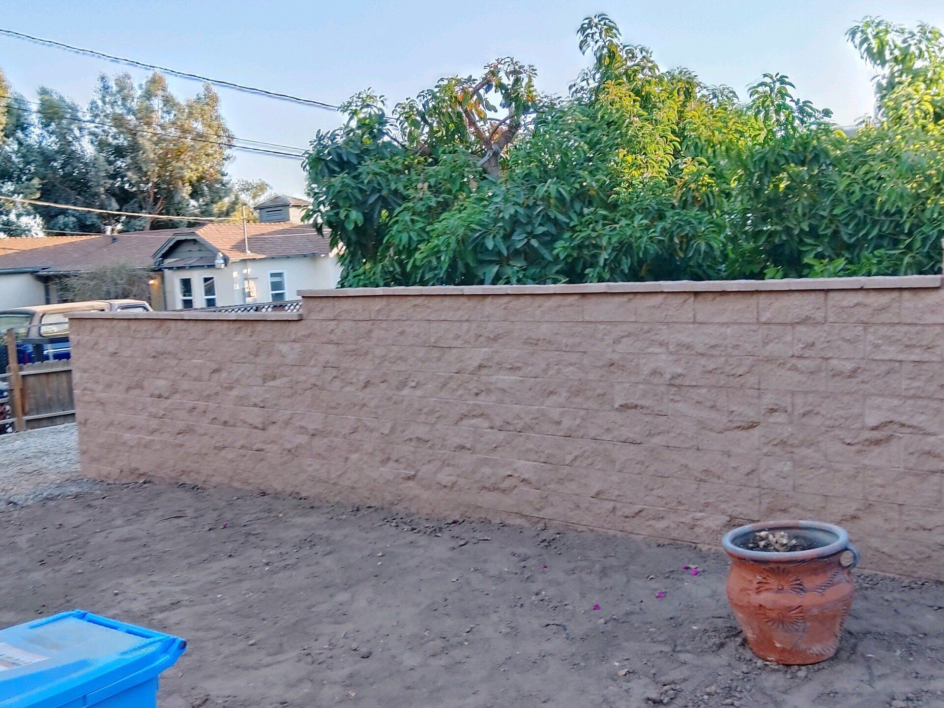 A brick wall with a pot in front of it