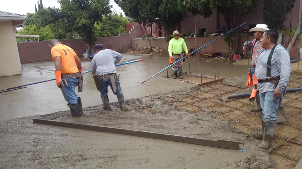 A group of construction workers are working on a concrete driveway.