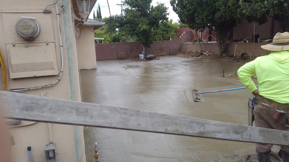 A man is standing on a concrete floor with a rake.
