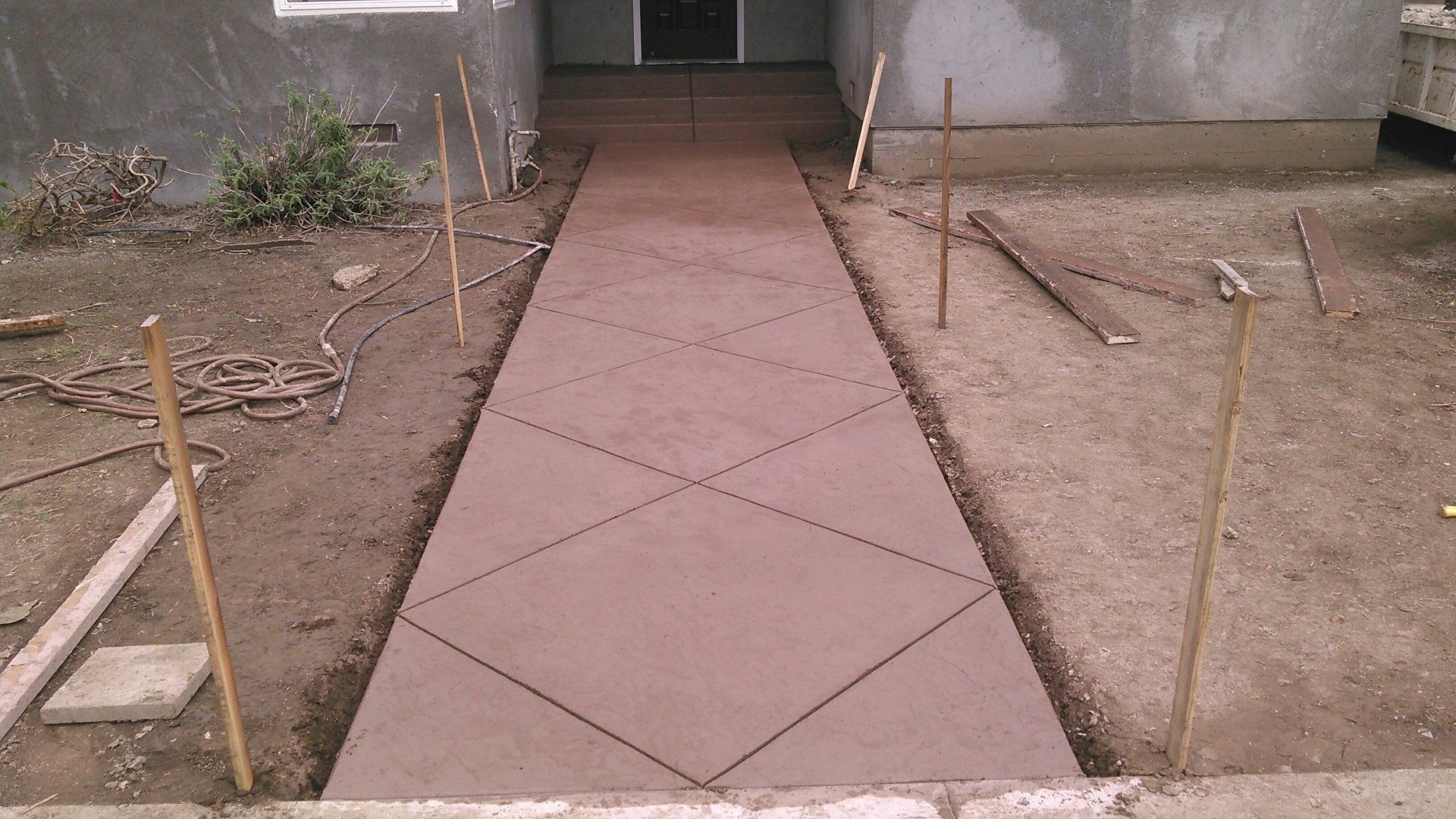 A concrete walkway is being built in front of a house.