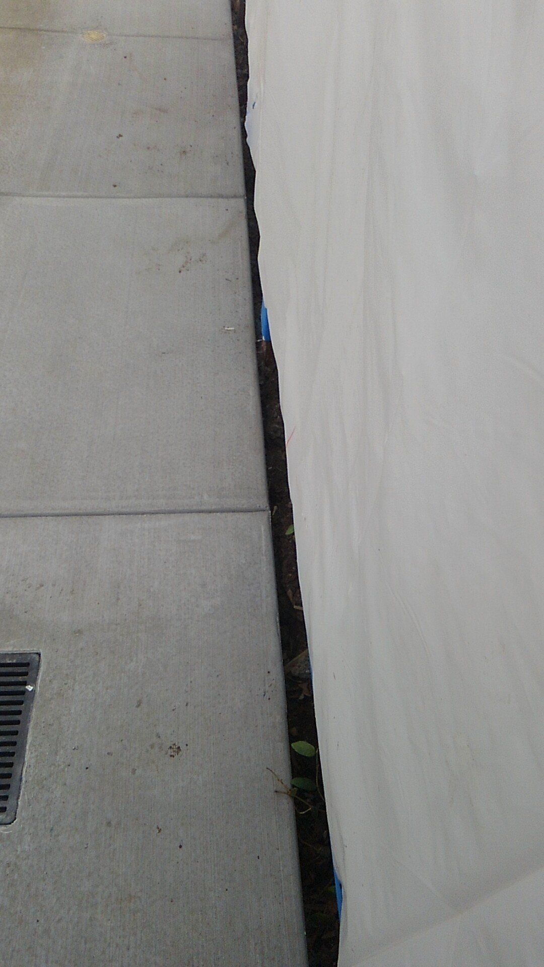 A white wall with a drain on the side of it.