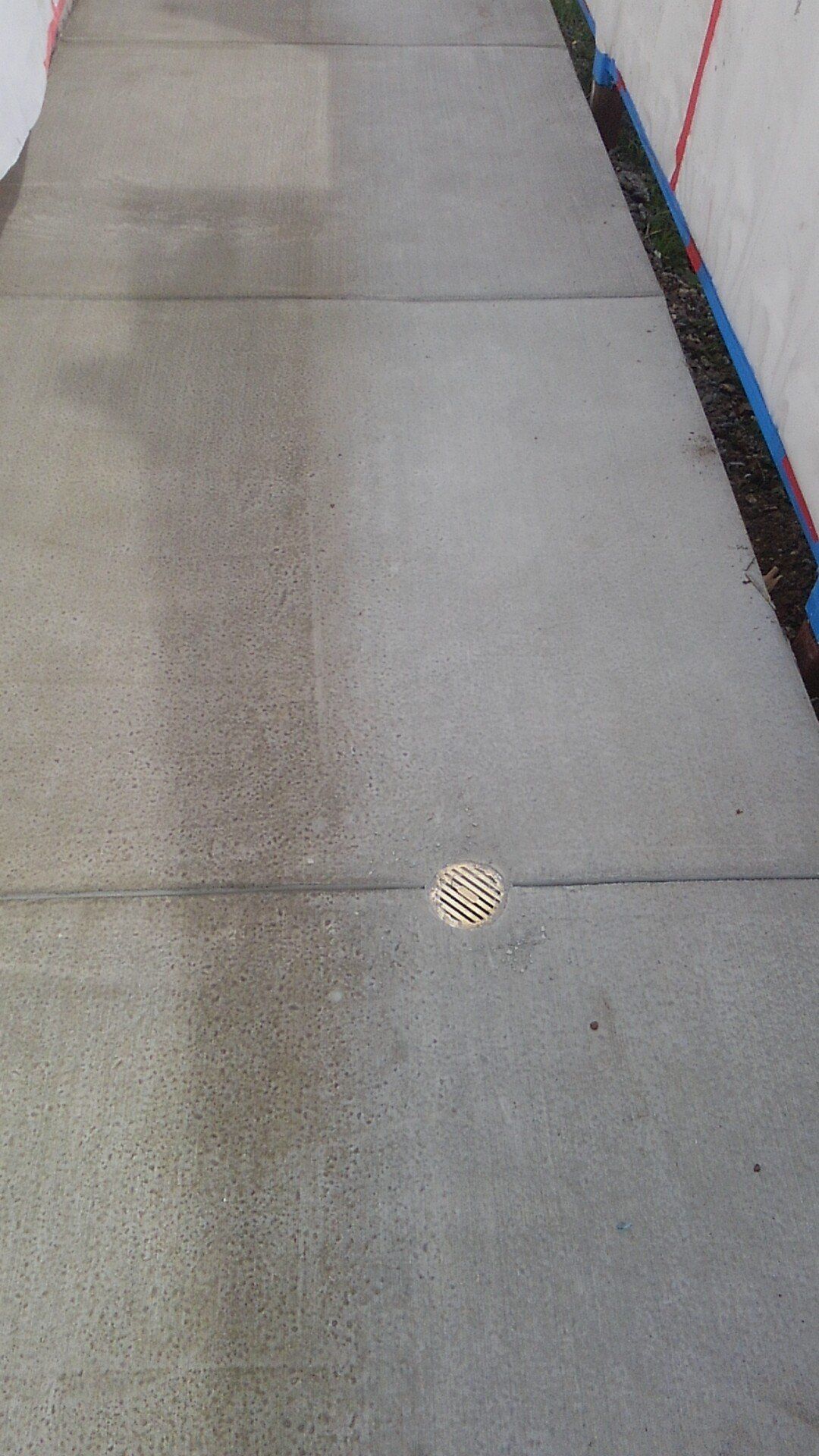 A concrete sidewalk with a drain in the middle of it.