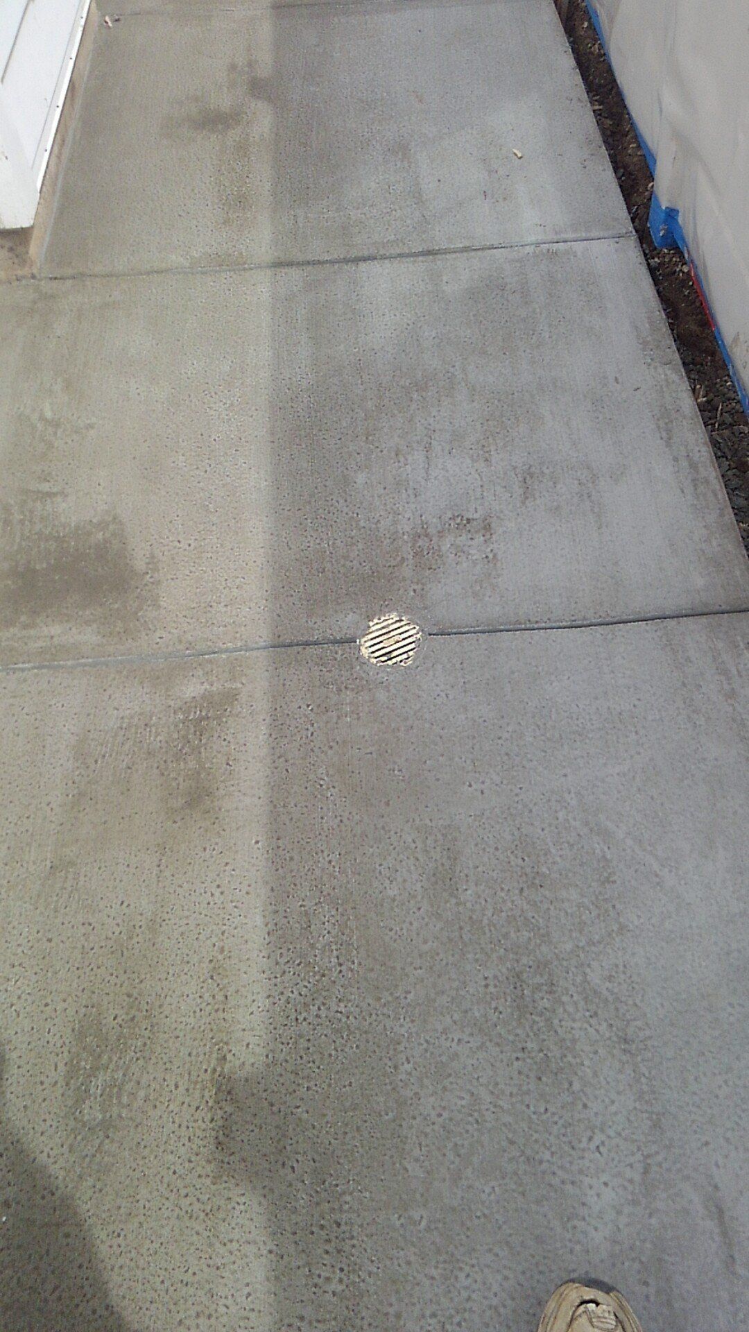 A concrete sidewalk with a drain in the middle of it.