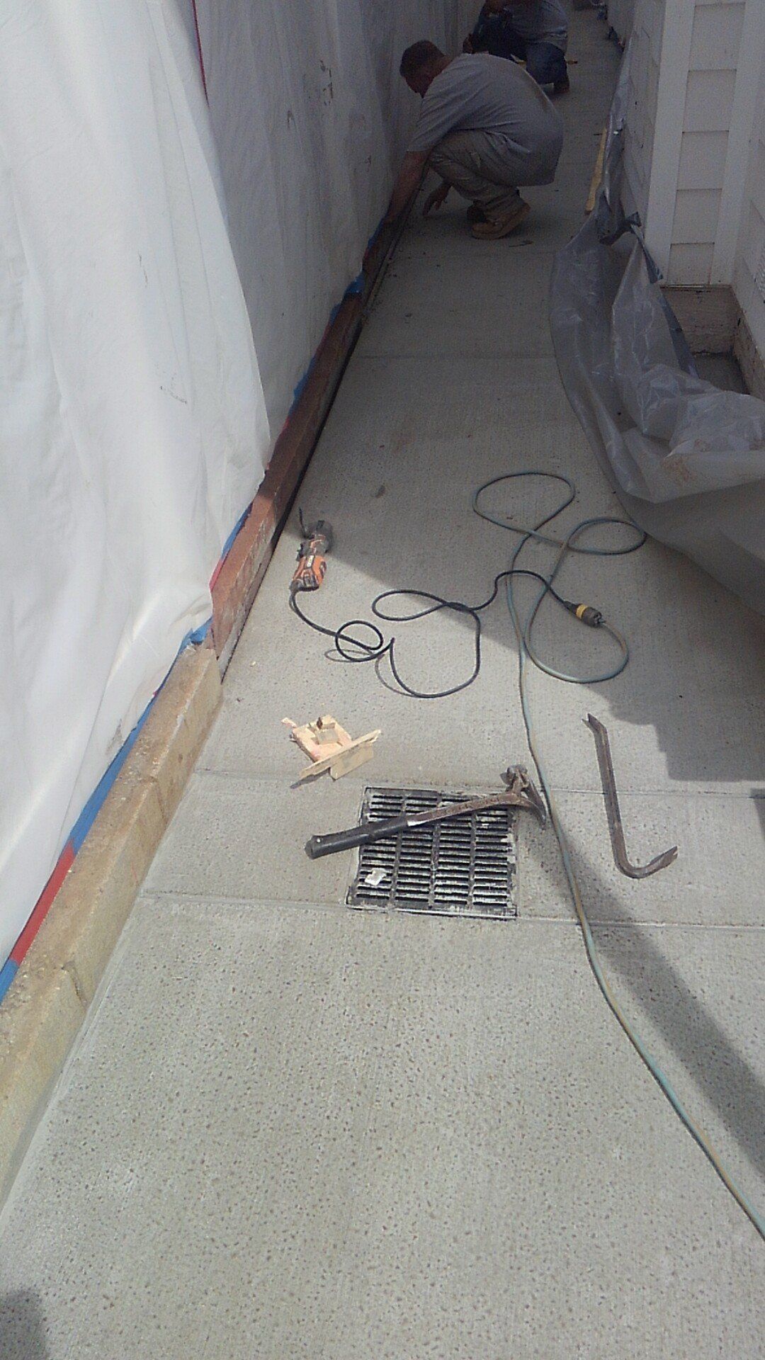 A man is working on a concrete floor next to a wall.